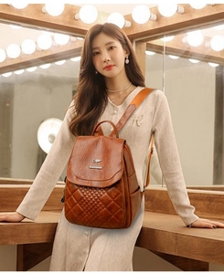 Close-up of caramel brown quilted backpack featuring vintage diamond stitching and metal logo