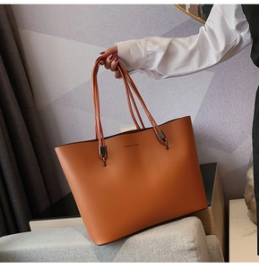 Close-up of caramel leather tote bag with Forever Young logo and long shoulder straps