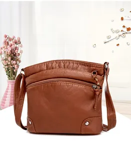 Detail view of vintage brown crossbody bag with multi-layer zippers and lychee grain texture