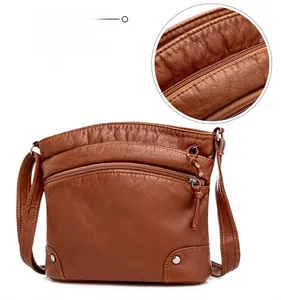 Detailed view of brown lychee-textured leather shoulder bag with multiple zipper compartments