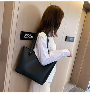 Elegant black lychee pattern leather tote bag shown being worn over the shoulder outdoors