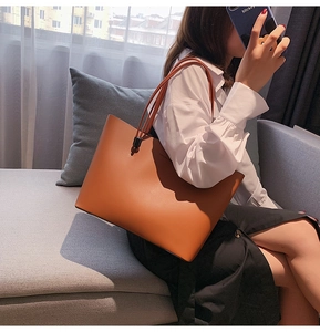 Detail of soft brown leather tote bag with Forever Young text and long shoulder straps