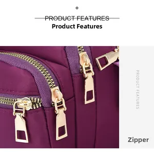 Detail view of smooth golden metal zippers on a purple twill nylon crossbody bag