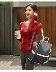 Detail of gray oxford backpack with cream trim and gray fur ball pendant accessory