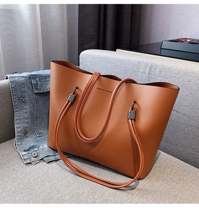 Close-up of a large brown leather tote bag with Forever Young text on a sofa
