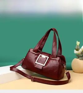 Close-up of vintage burgundy textured leather handbag with gold metal buckle and strap