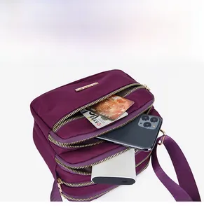 Close-up of purple nylon crossbody bag with four zipper pockets showing spacious storage