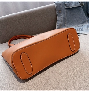 Close-up of caramel tote bag bottom with white contrast stitching and reinforced leather