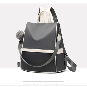 Detail of grey and white Oxford fabric backpack with detachable strap and pompom charm