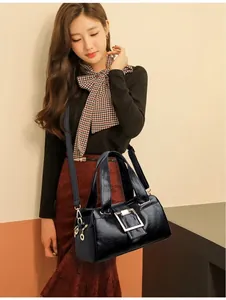 Detail of black leather handbag with silver square buckle worn by a female model