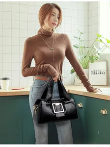 Detail of a black glossy handbag featuring a gold square buckle and leather texture
