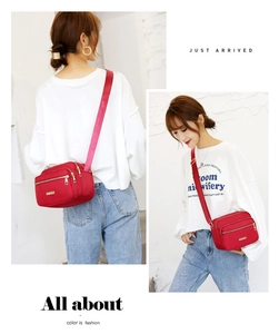 Detail of red nylon crossbody bag with multiple gold zippers and adjustable shoulder strap
