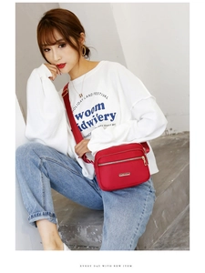 Outdoor shot of a red nylon crossbody bag showing size and capacity on a female model