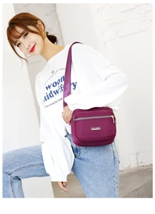 Detail of purple nylon crossbody bag with adjustable strap and multi-zipper pockets