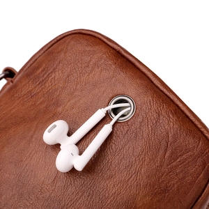 Brown textured leather crossbody bag with built-in headphone port and wired earphones