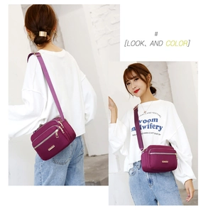 Front and back views of a purple nylon crossbody bag with gold zippers and metal logo