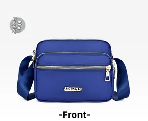Close-up of royal blue nylon crossbody bag with three zipper layers and gold logo plate