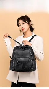 Detail of black leather backpack featuring geometric patchwork and silver metallic zippers