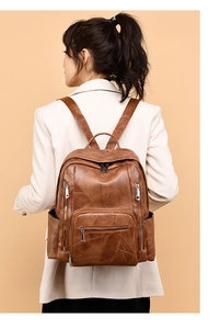 Brown retro leather backpack with geometric stitching worn by model in white suit