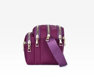 Detail view of purple nylon crossbody bag featuring four separate zipper compartments
