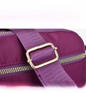 Detail of purple nylon bag featuring adjustable golden metal buckle and smooth zipper