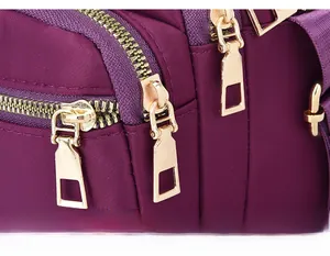 Detail of durable gold zippers on high-quality purple waterproof nylon crossbody bag