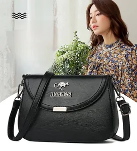 Detail of black pebbled leather crossbody bag with metal logo on floral dress model