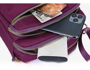 Detail of purple nylon crossbody bag showing three zipper compartments and large capacity