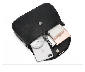 Top view of spacious interior of black faux leather bag showing daily essentials and flap closure