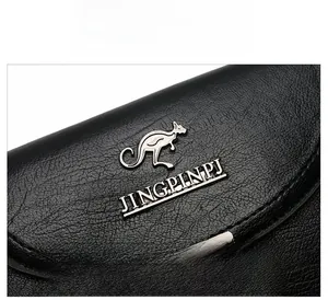 Close-up of black lychee grain leather with silver kangaroo metal logo and fine texture