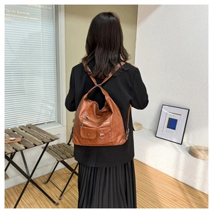 Vue arrière d'un mannequin portant un sac à dos vintage marron à plusieurs poches au café
