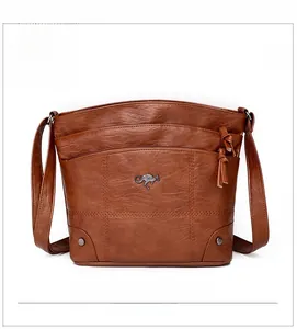 Gros plan d'un sac bandoulière en cuir marron avec logo kangourou et pompon zippé