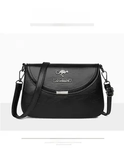 Detail of black faux leather crossbody bag with kangaroo metal logo and adjustable strap