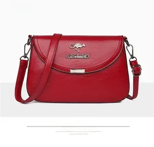 Detail of red faux leather crossbody bag featuring gold kangaroo logo and metal clasp