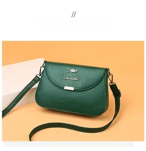 Close-up of dark green crossbody bag featuring pebble leather texture and metal logo