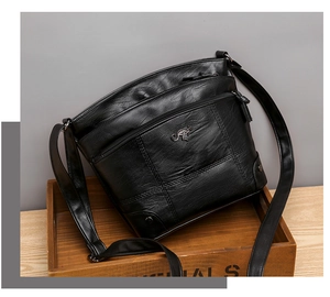 Vue détaillée du sac bandoulière en similicuir noir avec fermetures éclair et grain de cuir