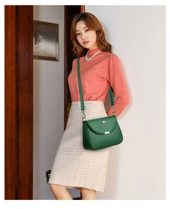 Detail of dark green leather crossbody bag with golden hardware and adjustable strap