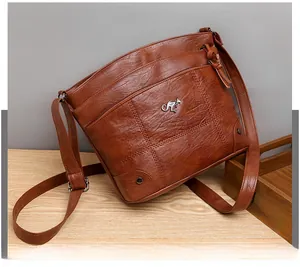 Détail du sac bandoulière en similicuir marron avec fermetures éclair et logo kangourou