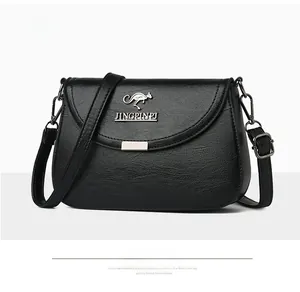 Detail of black pebbled leather crossbody bag with magnetic flap and kangaroo metal logo