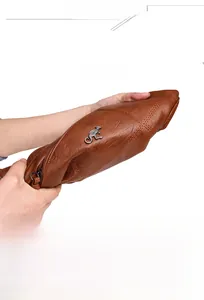 Détail montrant la texture flexible du cuir souple et le logo kangourou de ce sac marron