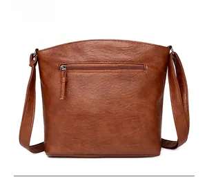 Détail du sac bandoulière en similicuir marron avec poche zippée au dos et texture grainée
