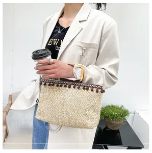 Detail of straw handbag with wooden round handles and stylish pompom fringe decor