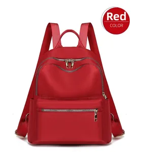 Vue de face d'un sac à dos de voyage rouge en nylon imperméable avec zips dorés