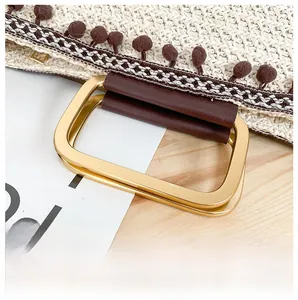 Detailed close-up of straw woven handbag with gold metal ring handle and tassel trim