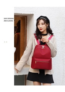 Détail du sac à dos rouge en nylon étanche avec fermetures éclair dorées et poches latérales