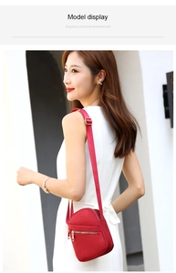 Red nylon crossbody bag with adjustable strap shown on model in a bright outdoor setting