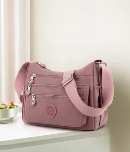 Detail view of pink nylon crossbody bag showing multiple zipper pockets and adjustable strap
