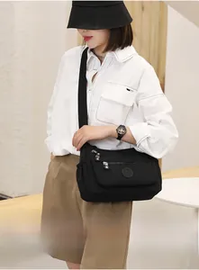 Detail view of black nylon crossbody bag with multiple zip pockets and adjustable strap