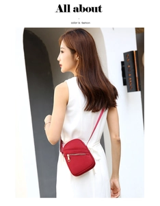 Close-up of red nylon crossbody bag with gold zipper detail worn by a model in casual setting