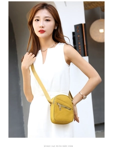 Detail of yellow nylon crossbody phone bag with wide strap and diagonal zipper pocket